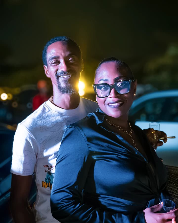 Un homme et une femme à lunettes sourient, lumières de la soirée en arrière-plan