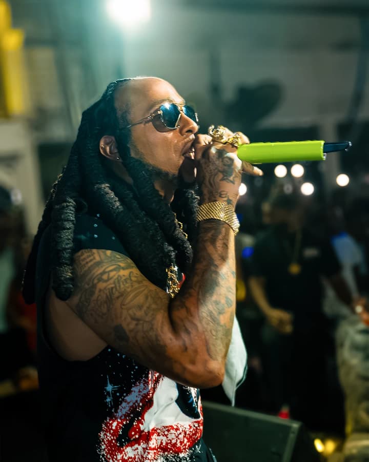 Un artiste aux longues dreadlocks chante au micro, lunettes de soleil