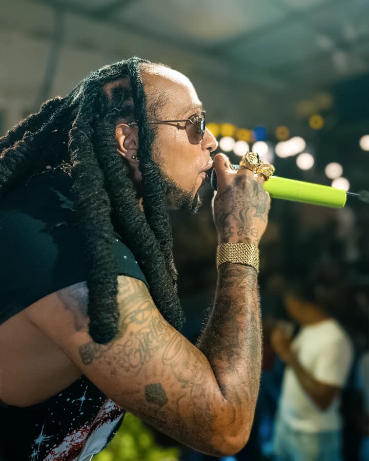 Profil d'un artiste qui chante, bras tatoués et bracelet doré