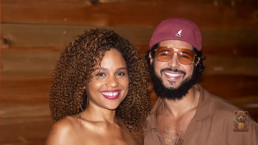 Un couple souriant devant un mur en bois