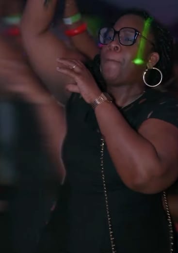 Une invitée danse, bras levés, sous les lumières de la soirée